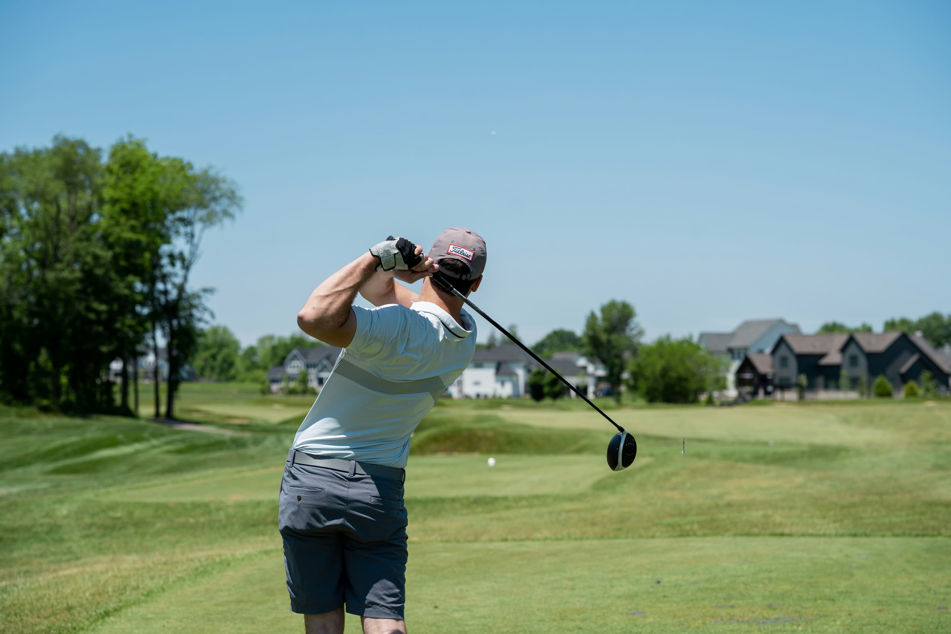 Titleist driver behind a golf ball on a tee at a Naples grass range