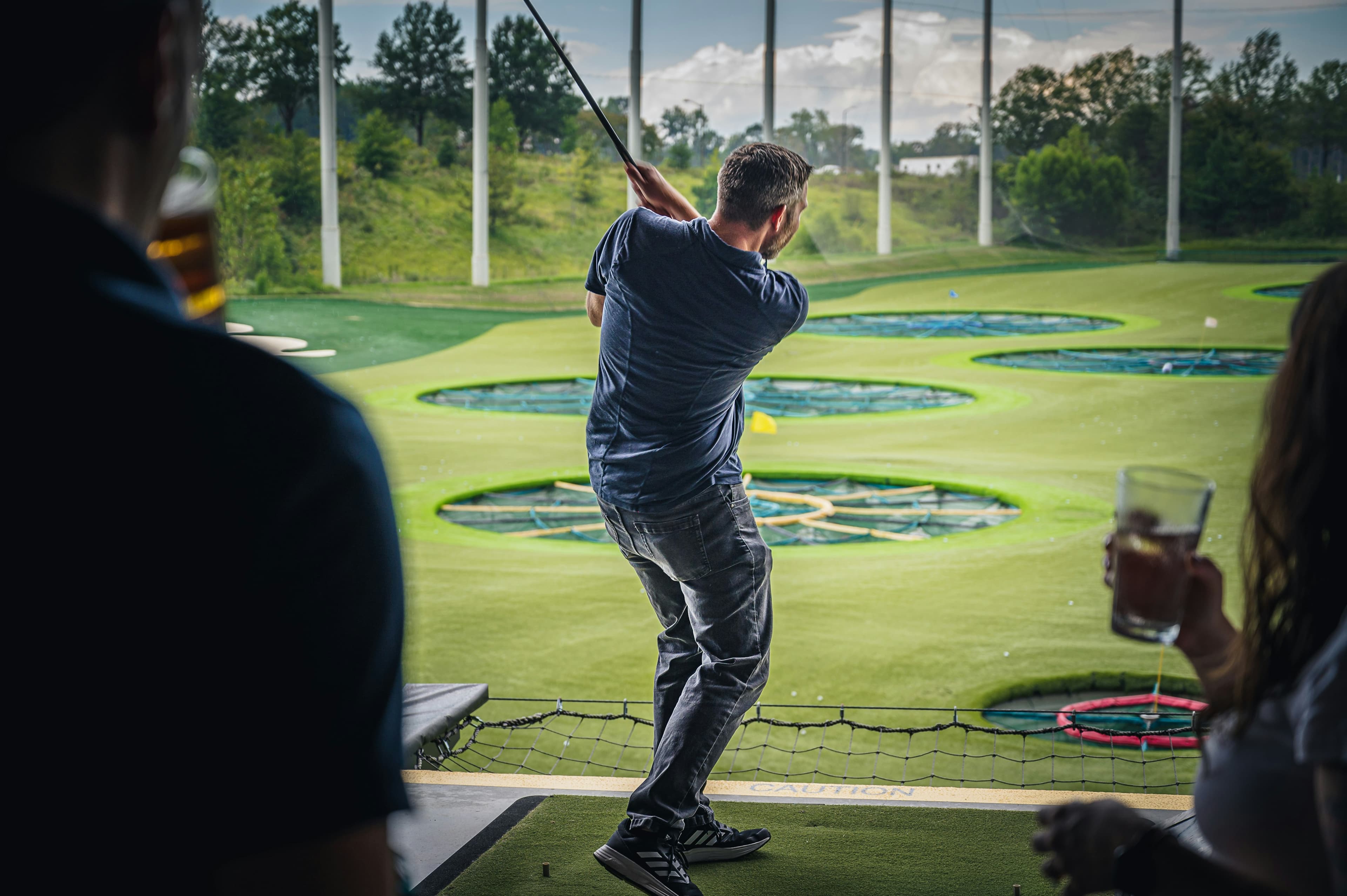 Golfer swinging at a Topgolf-style entertainment range in Orlando